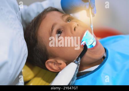 Mains, enfant et lumière de guérison dentaire pour le nettoyage des dents, la santé et l'hygiène bucco-dentaire à la clinique pédiatrique. Garçon, dentiste et traitement uv pour la dent, gros plan Banque D'Images