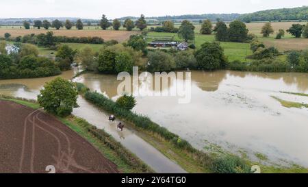 Les cavaliers font leur chemin à travers les eaux de crue à Walton dans le Warwickshire. 35 avertissements d'inondation sont en place dans toute l'Angleterre mardi matin. Certaines parties du Bedfordshire, de l'Oxfordshire, du Warwickshire et du Northamptonshire ont connu plus de 100 mm de pluie au cours des dernières 48 heures. Date de la photo : mardi 24 septembre 2024. Banque D'Images