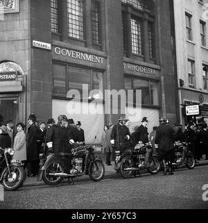 Les stores des fenêtres sont dessinés , et des policiers à moto et à pied montent la garde devant les bâtiments de la haute Commission Rhodésienne dans le Strand , Londres . Des renforts de la police se sont alignés devant le bâtiment cet après-midi alors qu'environ 150 étudiants de la London School of Economics marchaient sur le Strand . Plusieurs portaient des pancartes demandant des sanctions économiques contre M. Smith . 12 novembre 1965 Banque D'Images