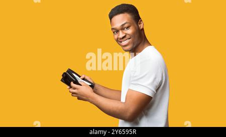 Portrait d'un homme noir montrant un portefeuille avec de l'argent Banque D'Images