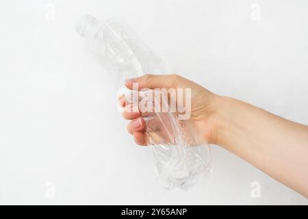 Main femelle coupée tenant une bouteille en plastique froissée. Sécurité et protection écologiques. Élimination et recyclage des déchets. Durabilité environnementale. Isolat Banque D'Images