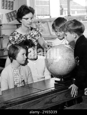 Ces élèves de neuf ans de Westwood Junior School , Welling , Kent étudient un globe du monde alors que leur enseignante , Mlle Edna Daines , pointe vers l'emplacement de la petite ville d'Aurora , près de Buffalo dans l'Etat de New York , Whee elle ira à la fin du trimestre . Miss Daines fait partie d'un groupe d'enseignants britanniques qui iront aux États-Unis dans le cadre d'un programme d'échange d'un an. Elle changera de place avec Mme Virginia Cornwall , de l'école élémentaire East Aurora . 5 juillet 1962 Banque D'Images