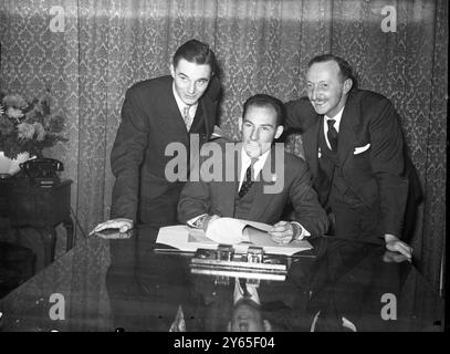 Sterling Moss signe un contrat Mercedes automobile britannique , année 25 Stirling Moss , a signé aujourd'hui un contrat avec les constructeurs automobiles allemands Mercedes Benz . Le contrat sera ensuite envoyé à Stuttgart , Allemagne , quand il sera signé par la société Meercedes Benz. De gauche à droite R . Bob Gregory ( directeur de Stirling Moss ) regarde le centre Stirling Moss , alors qu'il signe le contrat Mercedes Benz dans les bureaux de publicité de Dalton à Londres . A sa gauche se trouve M. Jerry amies , responsable des relations publiques pour Mercedes Benz en Angleterre le 9 décembre 1954 Banque D'Images