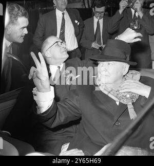 Sir Winston Chyrchill , 84 ans, ancien premier ministre de Heat , tire le bord de son chapeau vers le bas pour se protéger les yeux du soleil , tire son foulard pendant sa tournée électorale de Woodford , et donne son fameux signe ' V ' à ses électeurs . 6 octobre 1959 Banque D'Images