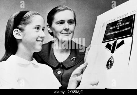 Washington DC , USA ; Dr Frances Kelsey avec sa fille Christine , 12 ans ( à gauche ) regardant la médaille qu'elle a reçu à la suite de son blocage de l'approbation américaine du médicament thalidomide . Kelsey a reçu le prix du Président pour service civil fédéral distingué du Président John F. Kennedy. Spécialiste de la Food and Drug Administration , elle aurait empêché une tragédie américaine en empêchant la commercialisation d'un somnifère , la thalidomide , plus tard liée à des malformations grotesques chez les nouveau-nés . 15 juillet 1962 Banque D'Images