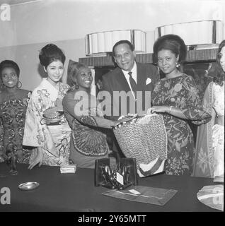 Quatre invités au Variety Club of Great Britain déjeunent au Savoy Hotel aujourd'hui au rythme d'un tambour bongo. De gauche à droite : Miss Japon Chikako Toyama, Miss Kenya, Zipporah Mbuga célèbre chef d'orchestre latino-américain Edmundo Ros, Miss Ouganda Rosemary Salmon. Après le déjeuner d'aujourd'hui, les concurrents de Miss World Beauty ont offert au comte Mountbatten de Birmanie des cadeaux, qu'ils broussent de leurs propres pays. Les articles doivent être utilisés pour recueillir des fonds pour les enfants malades et nécessiteux. 13 novembre 1967 Edmundo Ros est décédé le 22 octobre 2011 à l'âge de 100 ans. Banque D'Images