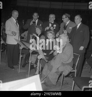 M. Herman Lindars , chef d'orchestre du Royal Philharmonic Orchestra , dirige le groupe de sept personnalités célèbres qui répètent sur une variété d'instruments de musique qu'ils joueront dans cette soirée Haydn, 'Toy Symphony' avec l'orchestre du Royal Albert Hall de Londres le concert est en aide au fonds 'Toy for the Sick Child' . Photo de gauche à droite , rangée arrière ; célèbre chef de groupe de danse , Edmundo Ros (trompette) , personnalité de la télévision , Lord Boothby (caille) , personnalité de la télévision , Cliff Michelmore (tambour) , ancien capitaine de cricket d'Angleterre , Sir Len Hutton (hochet). Photo - f Banque D'Images