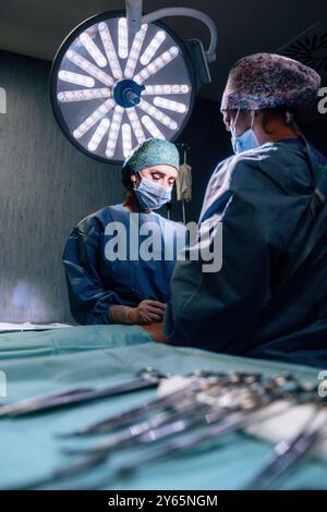 L'équipe chirurgicale s'est concentrée pendant une intervention dans une salle d'opération bien équipée, avec des lumières chirurgicales lumineuses et des instruments en vue Banque D'Images