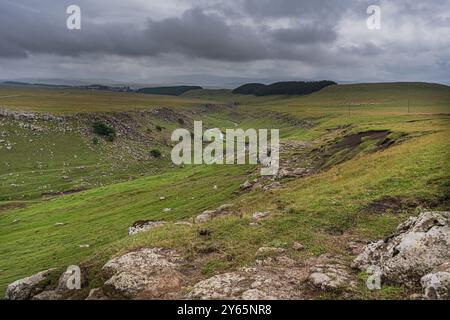 Cette image capture la beauté étendue de la campagne géorgienne, avec une rivière sinueuse flanquée de champs verdoyants et d'affleurements rocheux Banque D'Images