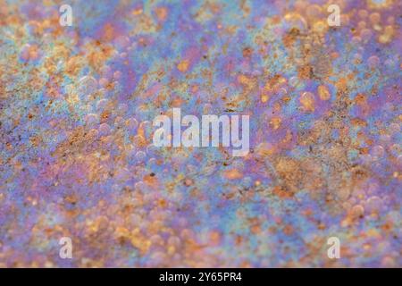 Capturant des couleurs vibrantes et des textures variées, cette image montre l'interaction de la lumière et des éléments dans une petite flaque d'eau, révélant un blen abstrait Banque D'Images