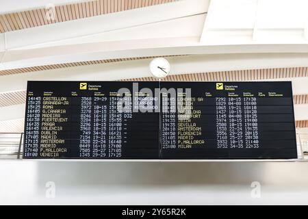 Les panneaux de départ de l'aéroport indiquant les horaires et les destinations des vols, avec une horloge sur le mur dans un terminal moderne, fournissent un instantané des fautes de frappe Banque D'Images