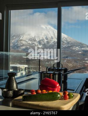 Une scène culinaire captivante surplombant le mont Yotei enneigé à Hokkaido, au Japon, avec des légumes frais sur une planche à découper et traditionnels Banque D'Images