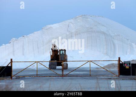 Un gros tas de sel avec une excavatrice devant une porte fermée dans une mine de sel. Banque D'Images