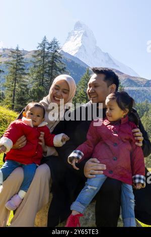 Une famille asiatique joyeuse avec deux petites filles et vêtue de vêtements d'automne décontractés, la mère portant un hijab souriant et profitant d'une journée ensoleillée à l'extérieur Banque D'Images