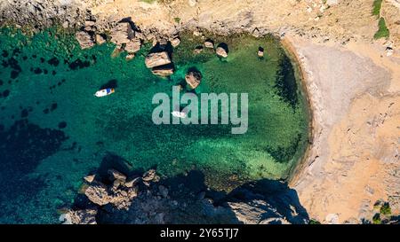 Cette image aérienne montre la superbe Cala Caldarer à Minorque, avec des eaux turquoises cristallines et des bateaux flottant doucement le mélange unique Banque D'Images