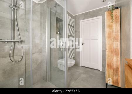 Intérieur moderne de salle de bains avec douche en verre, toilettes et porte-serviettes. Banque D'Images