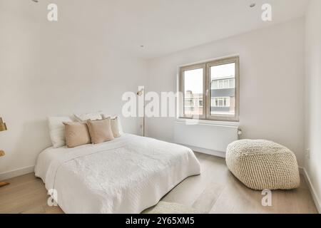 Cette chambre lumineuse et spacieuse au design minimaliste comprend un lit confortable, une grande fenêtre et des accents modernes. Banque D'Images