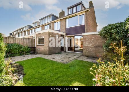 Une maison de banlieue moderne de deux étages avec une porte ouverte accueillante et un jardin bien entretenu à la lumière du jour. Banque D'Images