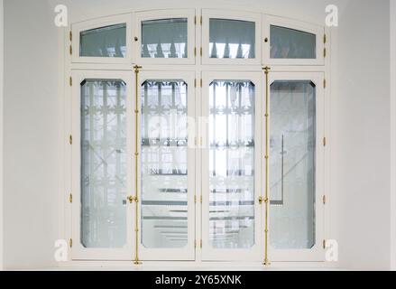 Une paire de portes françaises blanches élégantes avec verre translucide et poignées dorées améliore un bureau contemporain, offrant intimité tout en maintenant un A. Banque D'Images