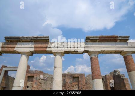 Colonnes blanchies à la chaux portant des inscriptions latines se dressent contre un ciel bleu vif au milieu des ruines de Pompéi les éléments historiques et architecturaux s'élèvent Banque D'Images