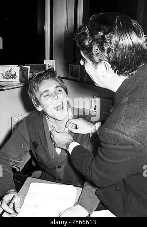 La pop star Billy Fury se fait vérifier la gorge par son manager Larry Parnes. Billy vient d'assurer ses cordes vocales pour un demi-million de livres 21 septembre 1966 Banque D'Images