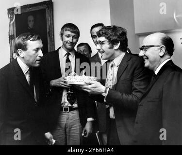 David Frost, personnalité de la télévision et intervieweur, jette un coup d'œil au gâteau d'anniversaire détenu par Kevin Billington qui réalisera le premier long métrage de M. Fros lors d'une réception organisée à Londres. La réception a eu lieu pour annoncer 'The Rise and Rise of Michael Rimmer' qui mettra en vedette John Cleese et Arthue Lowe. 12 juin 1969 Banque D'Images