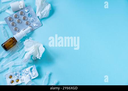 Médicaments et pilules arrière-plan. Saison des rhumes et des maladies. Concept de traitement. Spray nasal pour nez qui coule et mouchoirs en papier froissés sur backgr bleu Banque D'Images