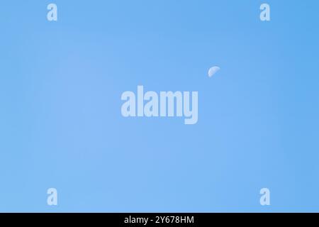 Un beau croissant de lune dans le ciel de l'après-midi. Un croissant de lune en plein jour contre un ciel bleu clair Banque D'Images