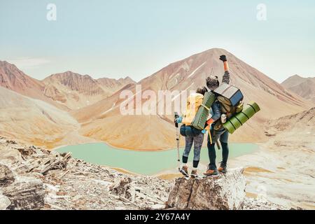 Deux randonneurs Célébrons les succès coucher de montagnes, accomplir avec les bras tendus. Jeune homme et femme à la belle à la source d'inspiration Banque D'Images