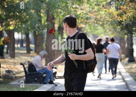 Homme avec des fleurs de rose marchant dans une rue sur fond de gens. Date dans la ville d'automne Banque D'Images