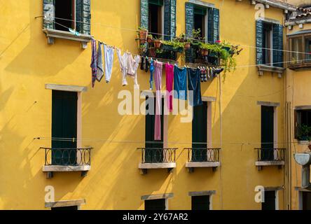 Linge suspendu à sécher sur une ligne de lavage suspendue entre deux bâtiments dans le sestiere San Marco de Venise, Italie Banque D'Images