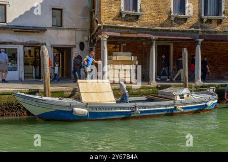 Hommes chargeant des caisses en bois contenant des objets de verre de Murano sur un bateau à Fondamenta Manin sur l'île de Murano près de Venise, Italie Banque D'Images