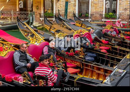 Un groupe de gondoliers prenant une pause assis dans leurs gondoles à Basino Orseolo dans le sestiere San Marco de Venise, Italie Banque D'Images