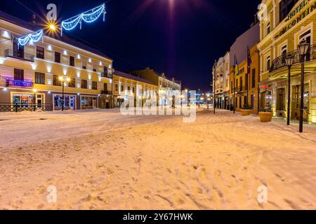 uzhhorod, ukraine - 06 janv. 2019 : paysage urbain hivernal la nuit. illumination de noël. rue couverte de neige. scène située près de la place petofi Banque D'Images