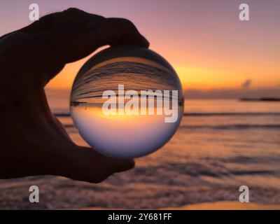 Main tenant boule de verre au lever du soleil, rêvant de nouveaux débuts Banque D'Images