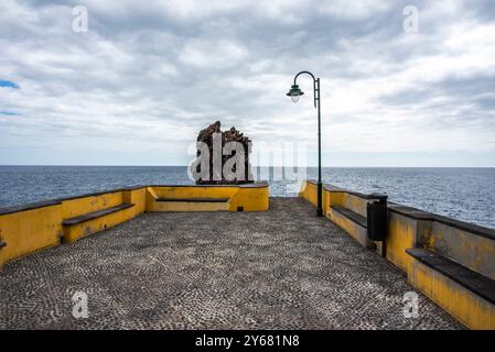 Imposante roche de lave se détache contre le ciel nuageux et les jetées de l'océan Atlantique à Ponta do sol à Madère Portugal Banque D'Images