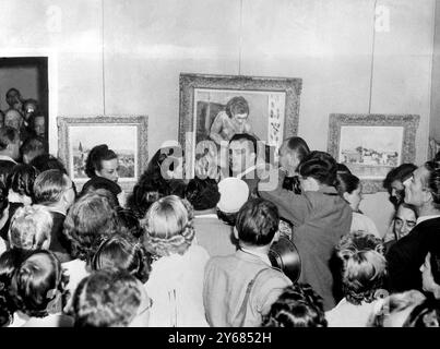 L'actrice de cinéma hollywoodienne, Rita Hayworth, et le prince Aly Khan, fils de l'Aga Khan, qui doivent se marier vendredi, ont été agacés lorsqu'ils ont rendu visite à une exposition d'art à la United States Art Gallery à Cannes. C'était la première apparition publique du prince Aly depuis qu'il s'est blessé au pied récemment, et la première apparition du couple depuis l'annonce de leur date de mariage. La photo montre le prince Aly (avec Rita sur sa gauche) regardant autour, un peu harcelé par la foule qui déferle autour d'eux à la galerie rendant l'appréciation agréable des images impossible. 23 mai 1949 Banque D'Images