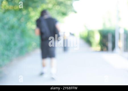 Arrière-plan flou, homme anonyme marchant le long de la route dans le parc. Journée ensoleillée d'été, Banque D'Images