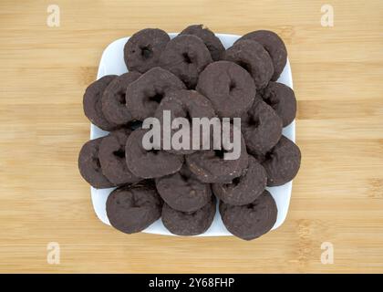 gros plan sur une assiette carrée avec des beignets ronds en chocolat sur une table en bois clair. Banque D'Images