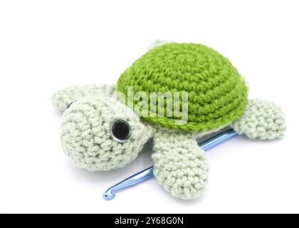 Gros plan sur une tortue crochet faite d'une main tenant un crochet crochet, la pose sur une surface blanche. Banque D'Images