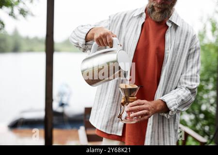 Photo recadrée d'un homme barbu en train de verser un café frais sur un espace de copie situé à l'extérieur dans un cadre naturel ensoleillé Banque D'Images