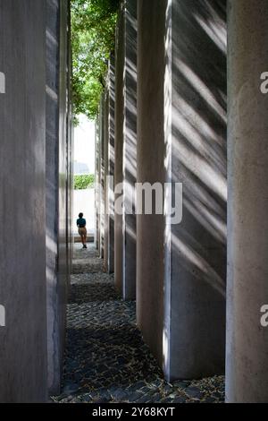 Berlin, Allemagne, juillet 27 2009, dans le jardin de l'exil, un visiteur marche à travers de hauts piliers de pierre sous la lumière du soleil, réfléchissant sur l'histoire et Re Banque D'Images