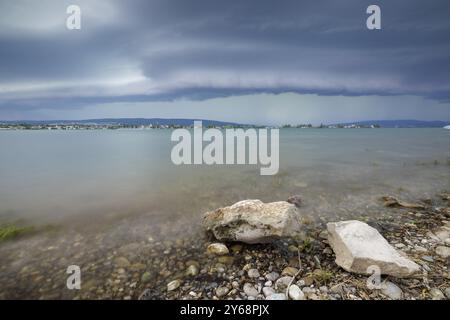 Ciel orageux sur un bord de lac calme avec des pierres et de l'eau claire, Allensbach, Untersee, lac de Constance, Constance District, Bade-Wuertemberg, Allemagne, E Banque D'Images