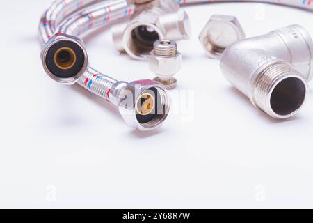 Un robinet d'eau et un tuyau dans une tresse métallique. Accessoires pour la réparation de l'alimentation en eau. Banque D'Images