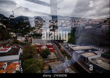 Vue depuis l'intérieur du téléphérique de funchal vers les collines ondulantes et les toits vibrants. Banque D'Images