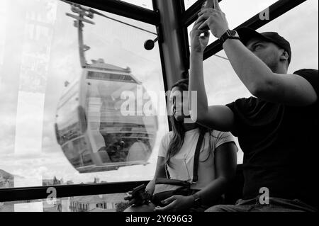 Monochrome, couple profitant de la vue et capturant des moments à l'intérieur du téléphérique de Funchal alors qu'une autre unité passe Banque D'Images