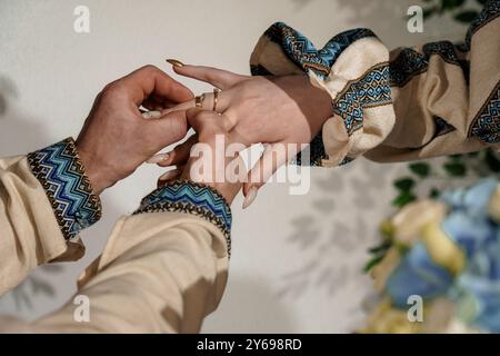 Cérémonie d'engagement romantique avec des anneaux élégants et des vêtements artistiques en éclairage doux. Banque D'Images