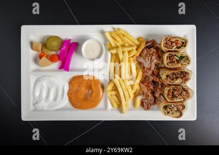 Shawarma de bœuf arabe avec frites frites, sauce à l'ail et cornichons dans une assiette blanche Banque D'Images