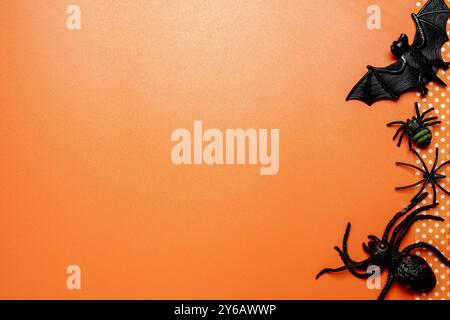 Un fond sur le thème d'Halloween avec un ruban orange, des araignées et une chauve-souris noire. Le fond est orange, ce qui ajoute à l'atmosphère effrayante du SC Banque D'Images