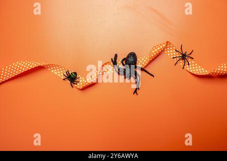 Un fond sur le thème d'Halloween avec un ruban orange et des araignées. L'arrière-plan est orange, ce qui ajoute à l'atmosphère effrayante de la scène. Effrayant Hal Banque D'Images